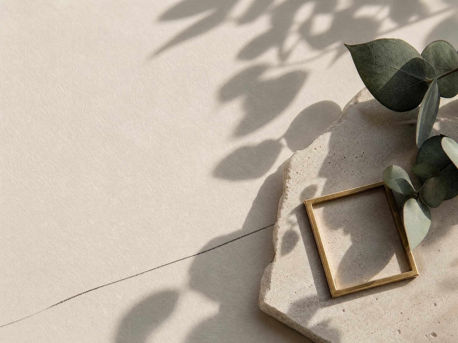 Stone tile with a brass frame and eucalyptus leaves on cream paper